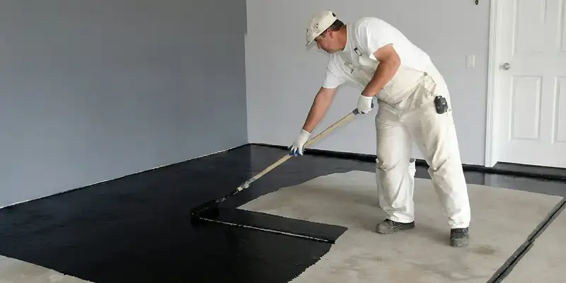 basement waterproofing professional applying waterproof coating to protect a basement floor in Milwaukee, WI